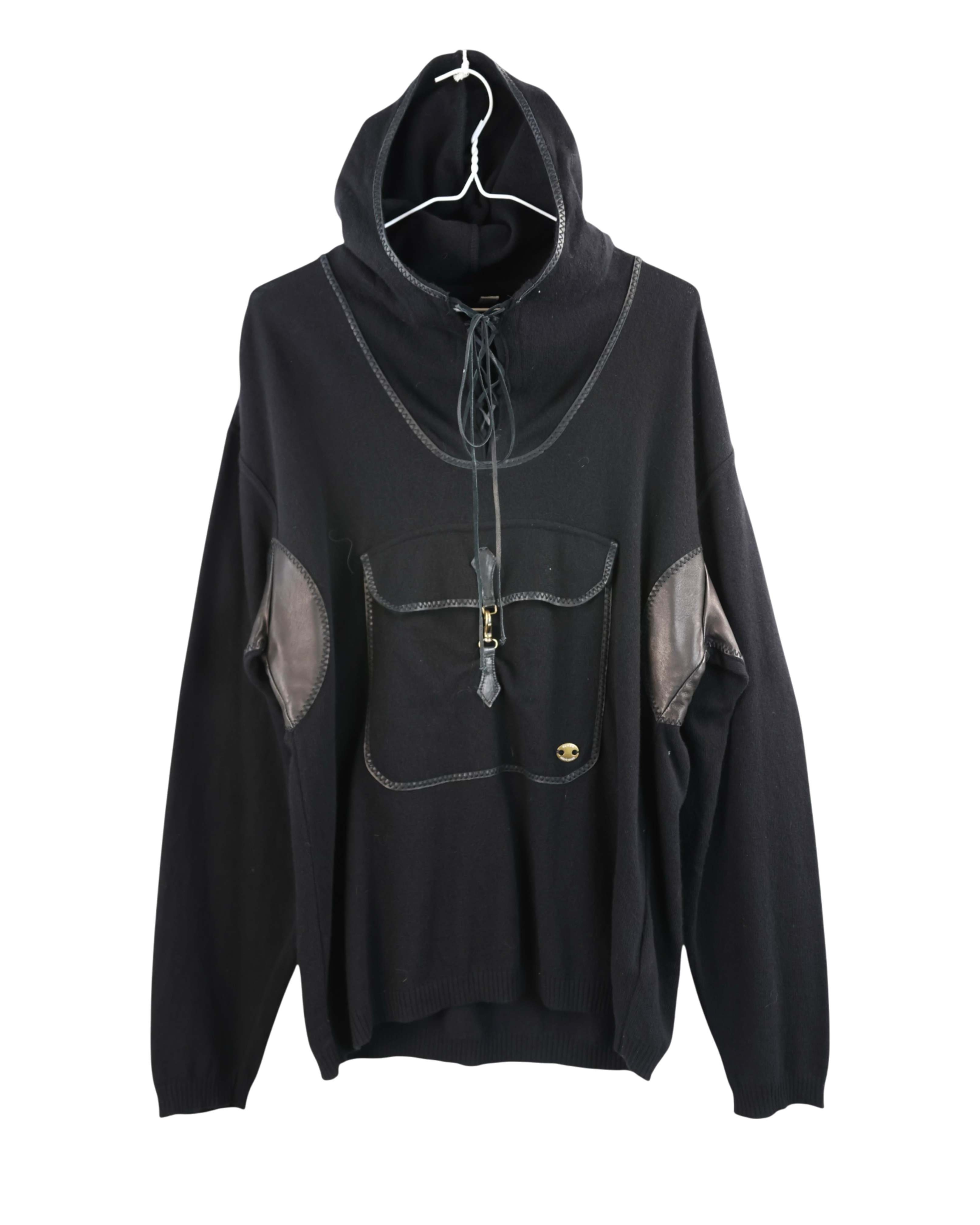 Black hoodie with gray accents on a white background. Roberto Cavalli Hooded Sweater. Roberto Cavalli black hooded knit sweater/hoodie; soft wool knit with leather-trimmed kangaroo pocket, leather elbow patches, lace-up neckline and contrast binding; relaxed/oversized fit, unisex; great with jeans, cargos, tailoring; style tags: rock, streetwear, Y2K, luxe casual; Italian luxury house craftsmanship, bold leather accents, collectible piece.