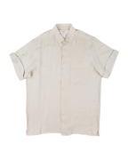 Beige short-sleeve shirt on a white background. Yohji Yamamoto off-white cream short-sleeve button-up shirt; smooth lightweight silk or rayon-like fabric with soft drape and minimalist tailoring; single chest pocket and tonal buttons; relaxed silhouette reflecting Japanese artisanal craftsmanship and understated avant-garde luxury typical of Yamamoto’s timeless design ethos.
