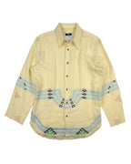 Beige shirt with decorative patterns on a white background. Vintage Voyage by Mazzilli & Michielsens embroidered dress shirt / button-down / collared top in pale butter yellow; geometric folk/tribal-inspired needlework in sky-blue, sage green and black across chest, sleeves and hem; long sleeves, pointed collar, curved hem, lightweight woven fabric for a relaxed tailored fit; artisan craftsmanship from Belgian designer duo (1990s–Y2K era); boho, artsy, gallery, festival, unisex styling—European luxury with 