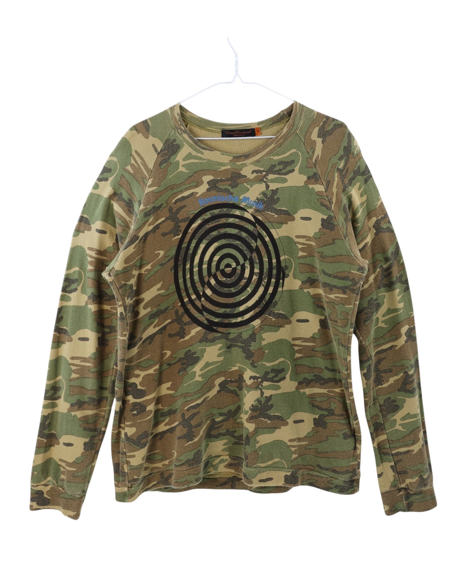 Camouflage sweatshirt with a black spiral design on a white background. Undercover camouflage/camo green cotton long-sleeve tee / T-shirt / top; front concentric target print with “Kosmische Musik” text; soft washed jersey, relaxed unisex fit; effortless with denim, cargos, techwear layers; style tags: punk, streetwear, military, avant-garde; brand context: Japanese cult label by Jun Takahashi, Tokyo artisanal design; rare graphic.