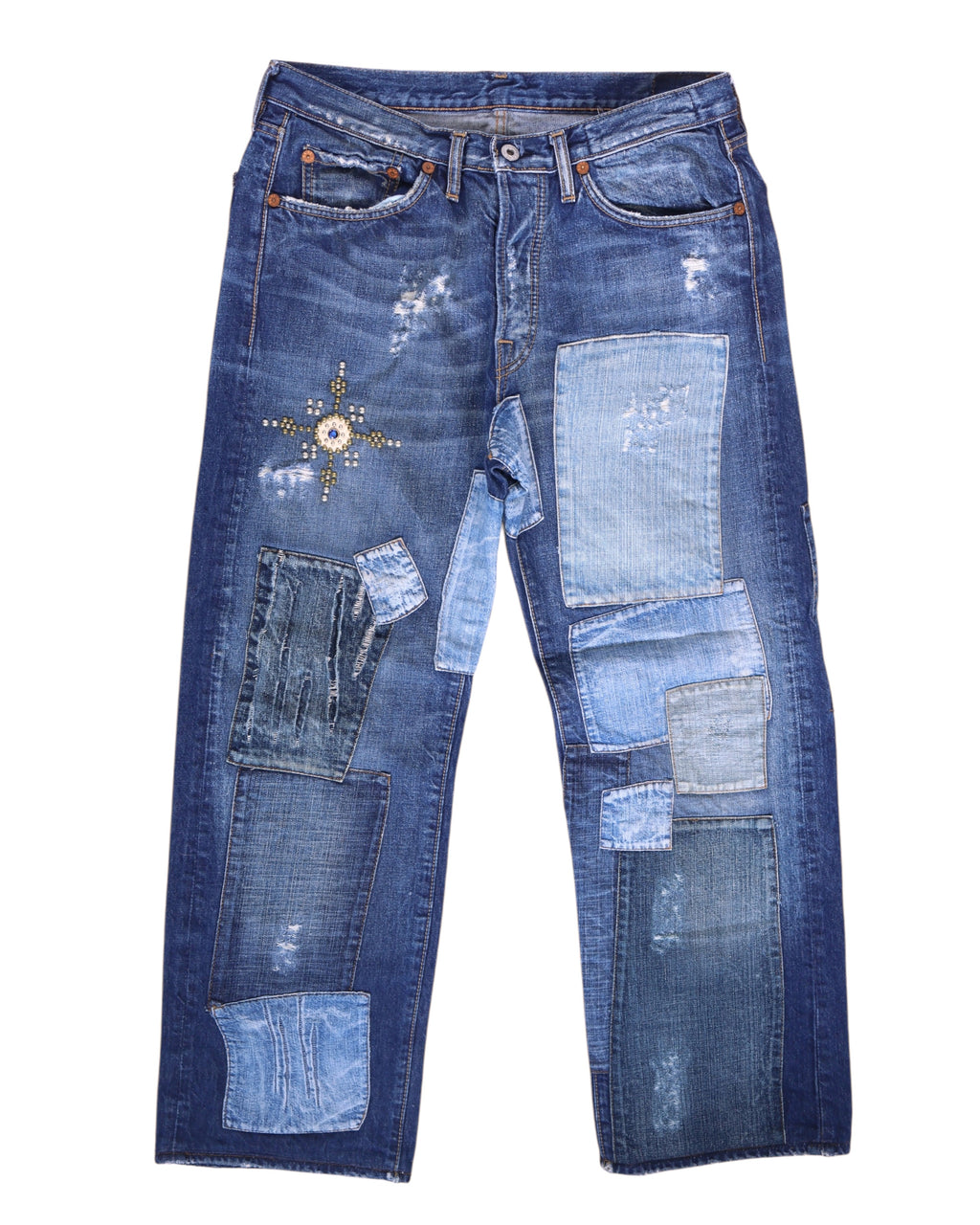 Vintage Ra-re medium-blue patchwork jeans/denim trousers featuring multi-shade repair panels, distressed wear and a studded star motif at the thigh; mid-rise straight leg with five pockets and button front. Luxury designer, rare and unique, laid flat on white.