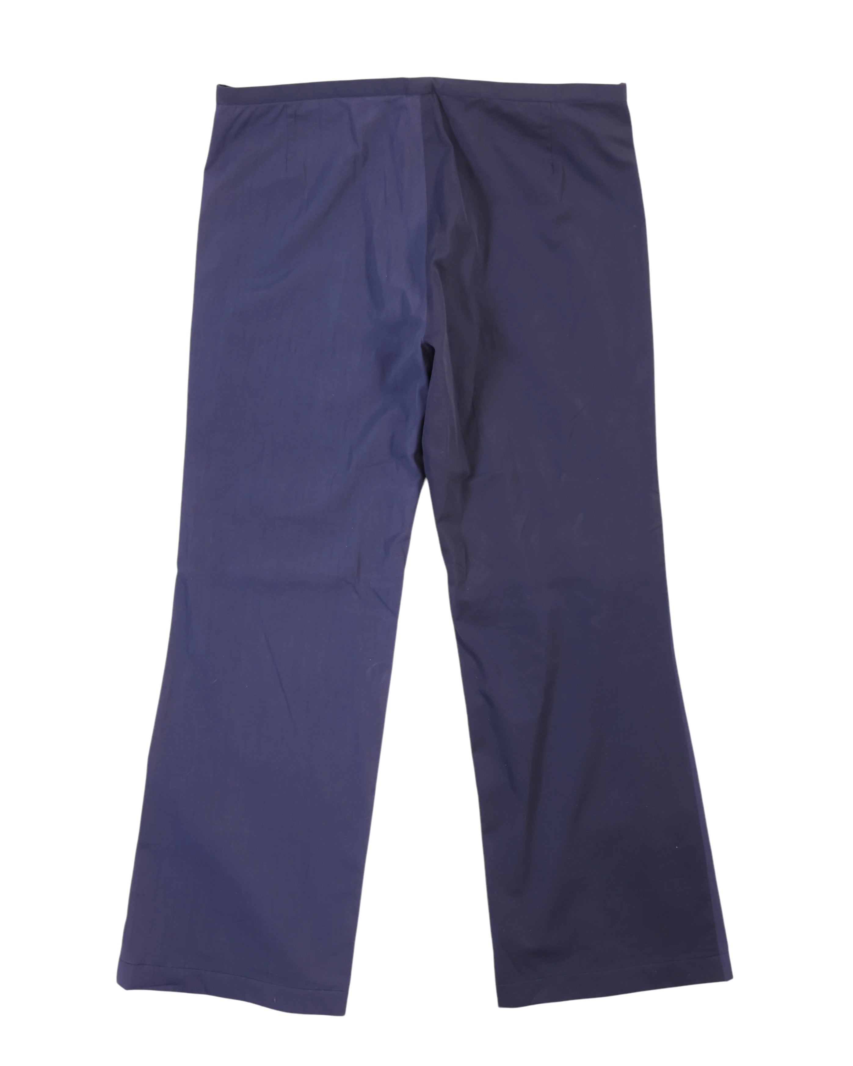 Back view of two-tone navy pants showing a split-panel design—indigo on one side, deep midnight blue on the other—with straight legs, plain waistband and smooth woven finish; refined, designer, unique.